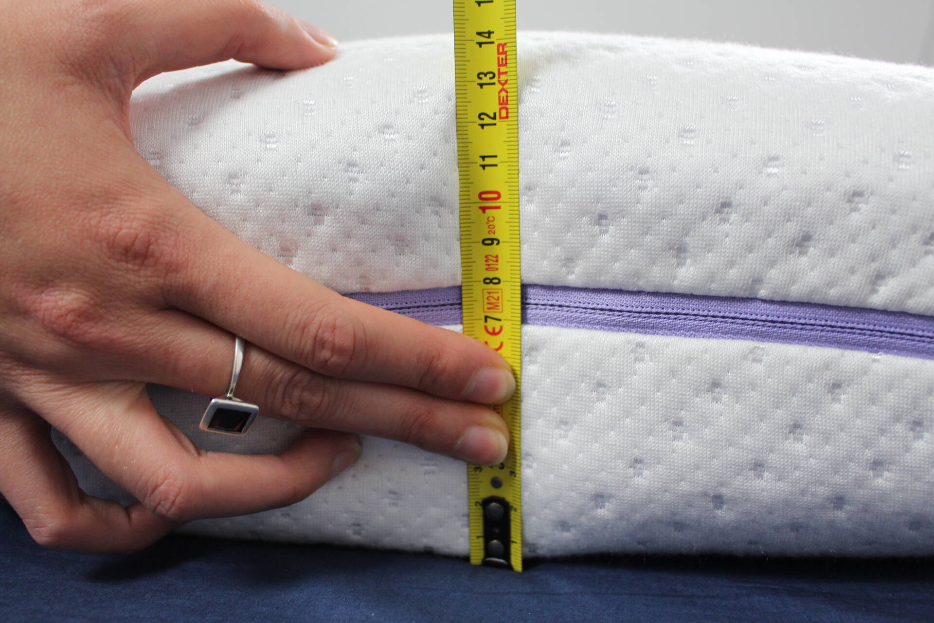 Person misst Kissen mit Maßstab